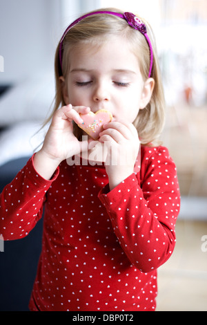 Little girl tasting a cookie, eye closed, Munich, Bavaria, Germany Stock Photo