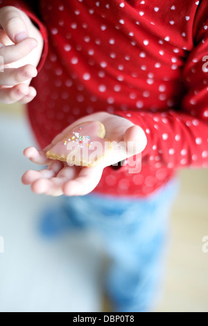 Little girl holding heart shaped cookie, Muich, Bavaria, Germany Stock Photo