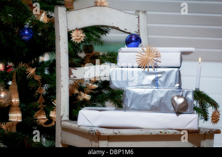 Gift boxes on a chair in front of Christmas tree, Munich, Bavaria, Germany Stock Photo