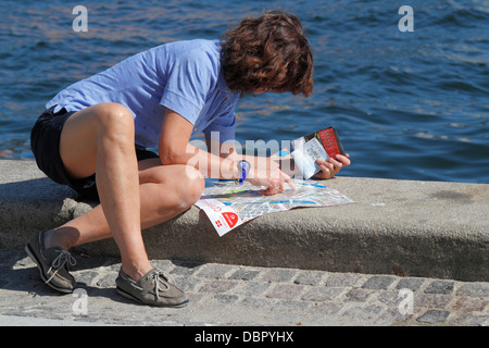 Female tourist studying the Copenhagen city map on the jetty near the Royal Playhouse in the port of Copenhagen. Stock Photo
