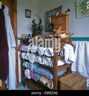 Rolled towels stored on old baker's rack in cottage bathroom Stock Photo