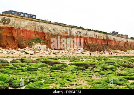 Hunstanton beach with red and white chalk striped cliffs and seaweeds algae covered rocks visible low tide, Norfolk, England Stock Photo