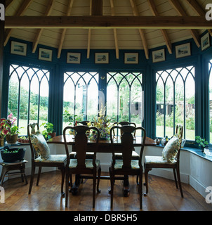 Antique table and chairs in  front of bay window in dining room with wooden floor and ceiling in newly-built Tudor-style house Stock Photo