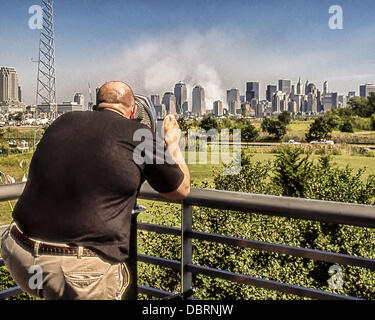 Sept. 12, 2001 - New York, New York, US - A spectator at the Liberty Science Center, Jersey City, N.J. views the smoke still billowing into the sky over lower Manhattan from ground zero, the former site of the World Trade Center, the day after terrorists crashed two hijacked airliners bringing down the twin 110-story towers. (Credit Image: © Arnold Drapkin/ZUMAPRESS.com) Stock Photo