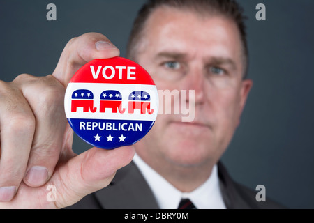 A politician holds up a republican voting badge encouraging his pundants to vote. Stock Photo
