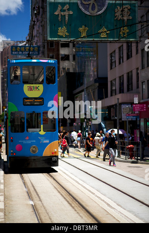 Tram stopped in Wan Chai to pick up and drop off passengers.  The tram is decorated with the HK tourism board Stock Photo