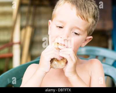 Little boy eating a sandwich outdoors in a summer day Stock Photo