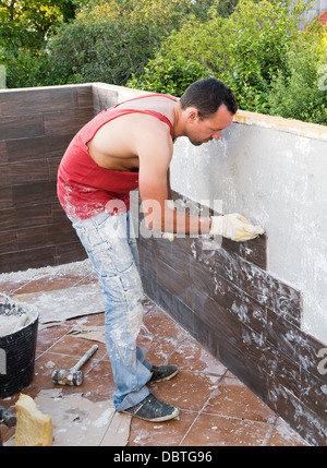 Stonemason on a house. The builder is putting a small wall plaque in a terrace. Stock Photo