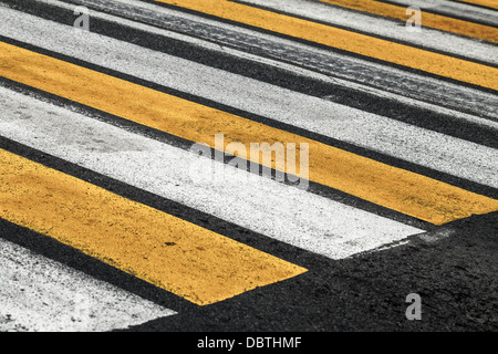 Pedestrian crossing road marking with yellow and white stripes on asphalt road Stock Photo