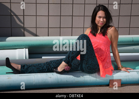 Fashionable woman sitting on industrial pipes Stock Photo