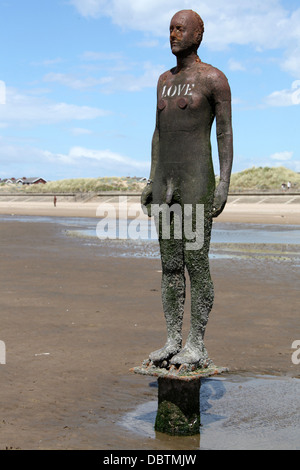 LOVE written on one of the Antony Gormley statues called Another Place at Crosby beach. Stock Photo