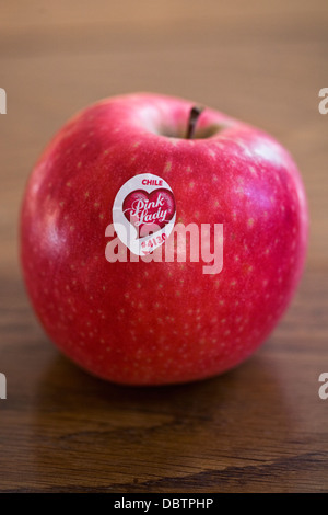 Single Pink Lady apple on a wooden table. Stock Photo