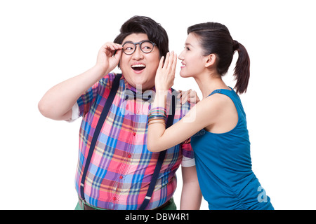 Young woman whispering in fat man's ear Stock Photo