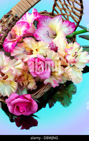 bouquet of gladioli and roses are in a wicker basket
