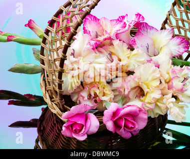 bouquet of gladioli and roses are in a wicker basket