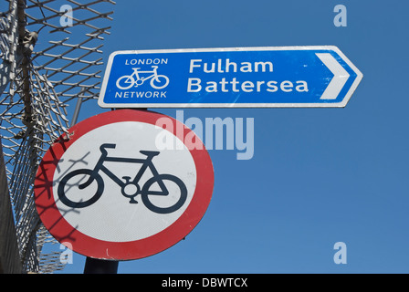 road sign denoting no cycling beside a cycle route sign with directions to fulham and battersea, in wandsworth, london, england Stock Photo