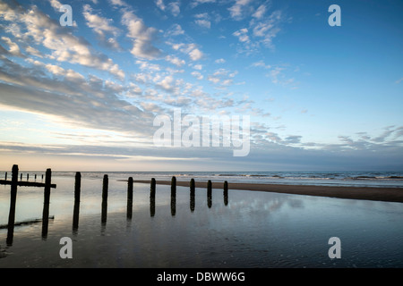 Beautiful sunrise reflected in low tide water pools on beach landscape Stock Photo