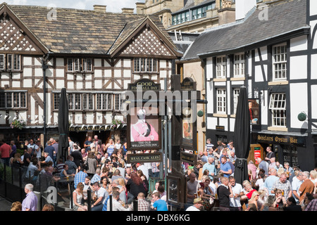 Crowds of people outside 16th century timbered The Old Wellington Inn 1552 in summer in crowded beer garden. Shambles Square Manchester England UK Stock Photo