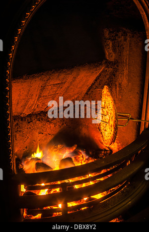 Bread being toasted by an open coal fire in Winter. Stock Photo