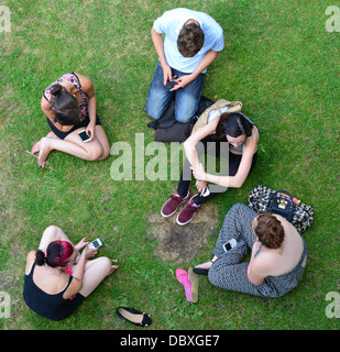 Group of young students sitting on riverbank at Goring Lock, Goring-on-Thames, Oxfordshire, England, United Kingdom Stock Photo