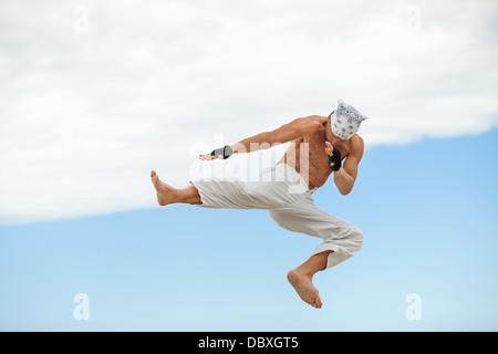 man is jumping sport karate martial arts fight kick jump beach summertime Stock Photo