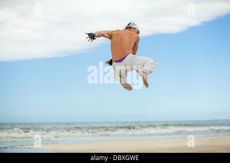 man is jumping sport karate martial arts fight kick jump beach summertime Stock Photo