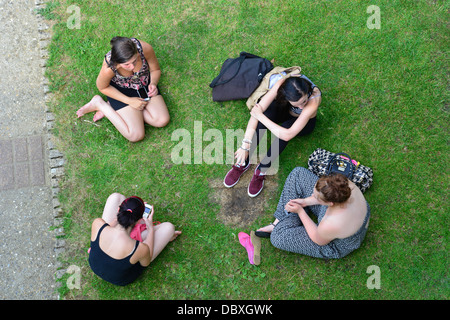 Group of young students sitting on riverbank at Goring Lock, Goring-on-Thames, Oxfordshire, England, United Kingdom