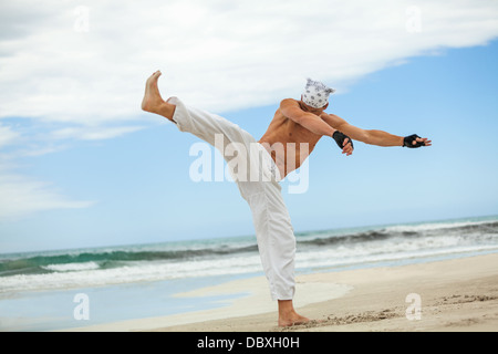 man is jumping sport karate martial arts fight kick jump beach summertime Stock Photo