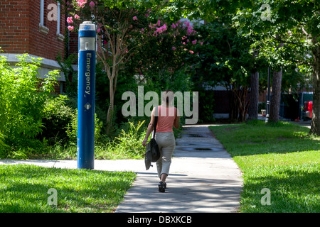 Woman walking by blue campus emergency call station. Stock Photo