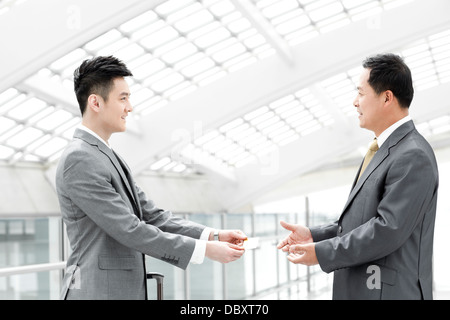 Business associates exchanging business card in airport lobby Stock Photo
