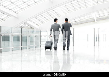 Business associates walking and talking in airport lobby Stock Photo