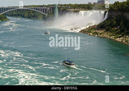 Maid of the Mist boats near the American Falls and the Rainbow Bridge border crossing.  From the Canadian side of Niagara Falls. Stock Photo