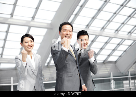 Excited business people celebrating in airport lobby Stock Photo