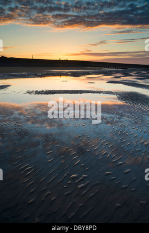 Beautiful sunrise reflected in low tide water pools on beach landscape Stock Photo