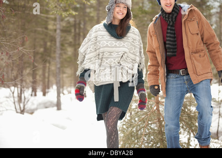 Couple dragging fresh Christmas tree in snowy field Stock Photo