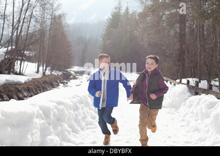 Boys holding hands and running in snowy lane Stock Photo