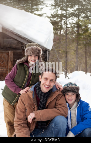 Portrait of smiling father and sons in snow outside cabin Stock Photo