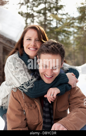 Portrait of hugging couple outside snowy cabin Stock Photo