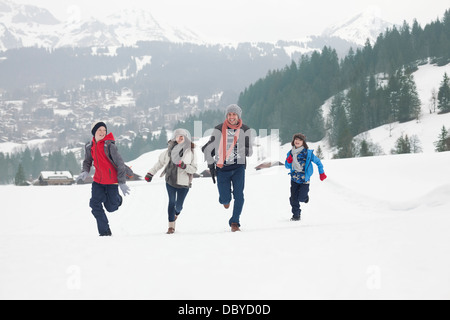 Family running in snowy field Stock Photo