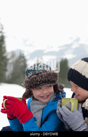 Close up of happy boys drinking hot chocolate in snowy field Stock Photo