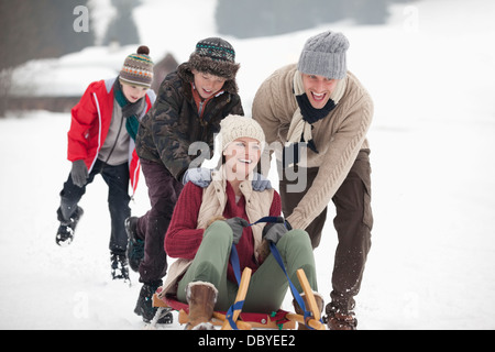 Happy family sledding in snowy field Stock Photo