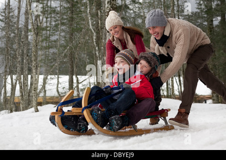 Happy family sledding in snowy woods Stock Photo