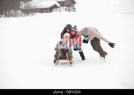 Happy family sledding in snowy field Stock Photo