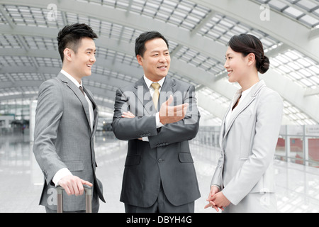 Happy business associates having conversation in airport lobby Stock Photo