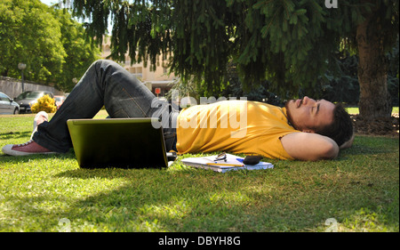 college student lying on the grass in the sun Stock Photo