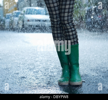 Rain falling around woman in wellingtons Stock Photo