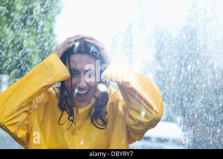 Happy woman with hands on head in rain Stock Photo