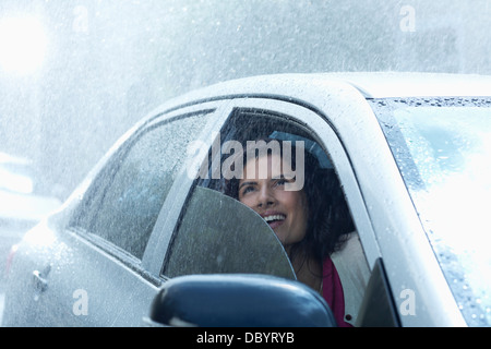 Smiling businesswoman in car looking up at rain Stock Photo