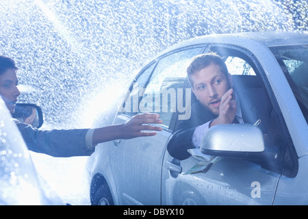 Businessman in car providing directions to woman in rain Stock Photo