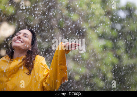 Happy woman standing with arms outstretched in rain Stock Photo
